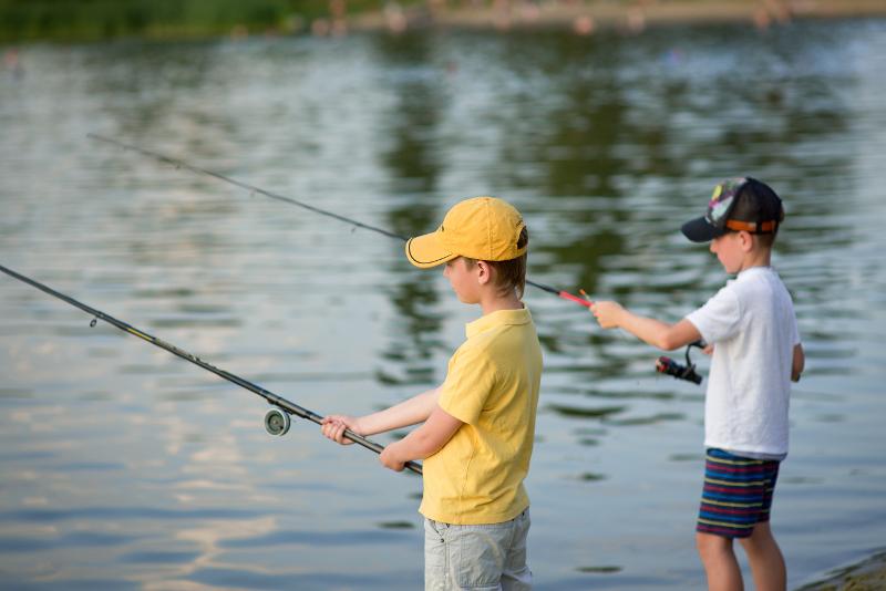 garçons qui tiennent une canne à pêche au bord de l'eau avec une casquette