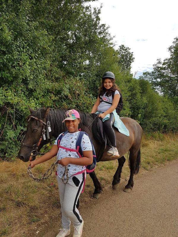enfant qui fait du cheval en extérieur en colo