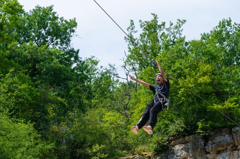 jeune qui fait de la tyrolienne dans la nature