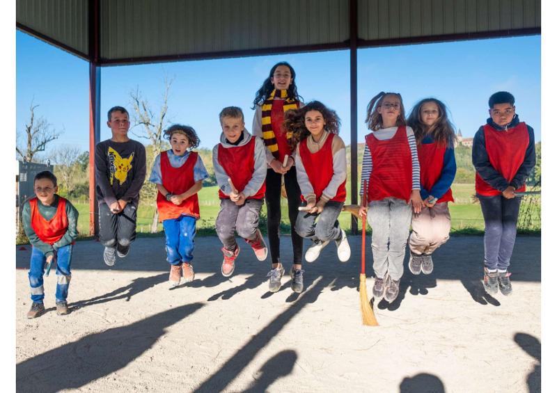 groupe d'enfants déguisés en sorciers qui font une photo de groupe en sautant et en s'amusant