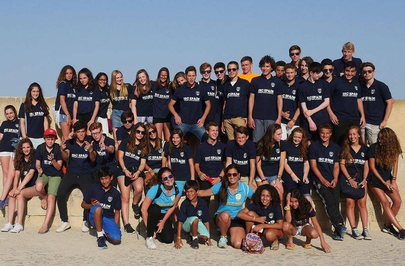 groupe de jeunes avec un t-shirt noir qui posent au soleil sur le sable
