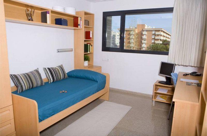 chambre d'un campus lors des séjour de langue espagnol avec un lit, des étagères, une fenêtre et un bureau