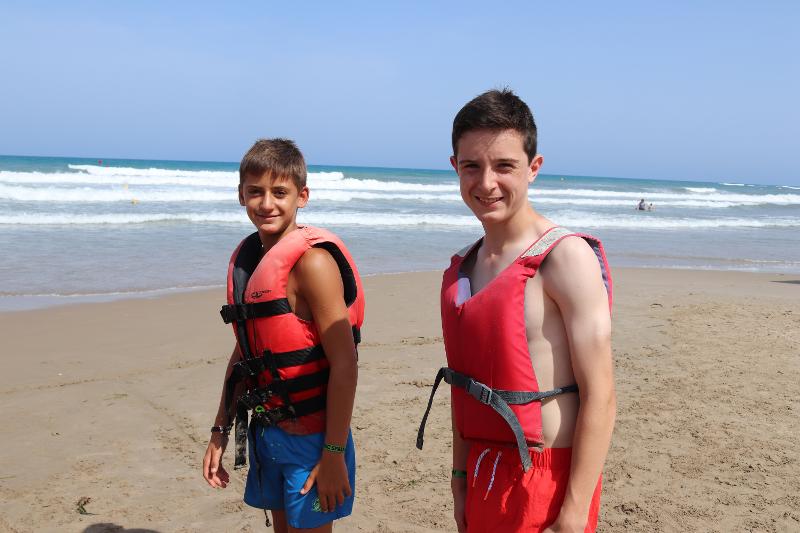 deux garçons sur la plage avec des gilets de sauvetage qui sourient durant un séjour linguistique Espagne ado