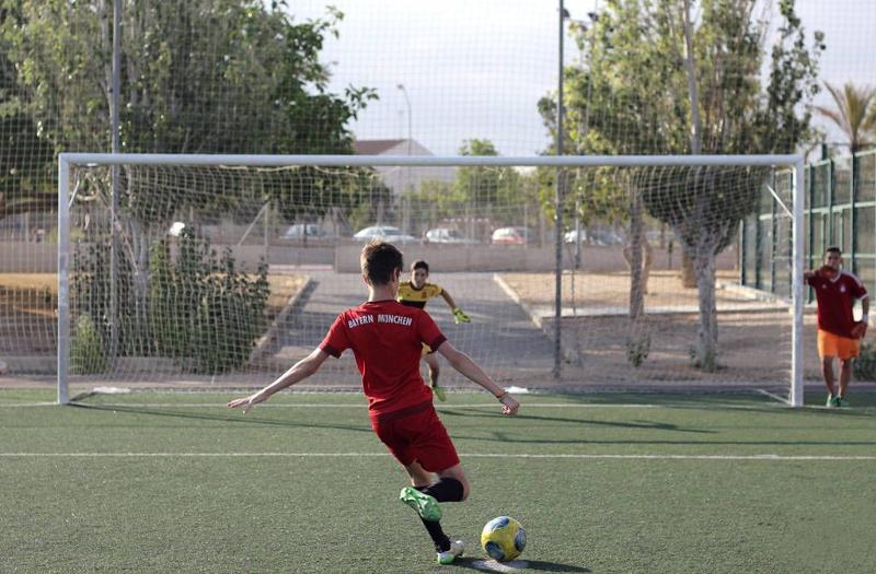 enfants qui jouent au foot en plein air en colo avec un jeune qui va marquer un but