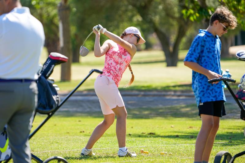 fille habillée en rose qui fait un swing sur un terrain de golf en stage de langue espagnol