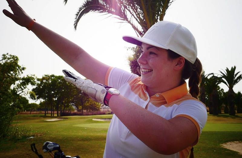 une fille qui dab avec une casquette blanche et des gants sur un terrain de golf