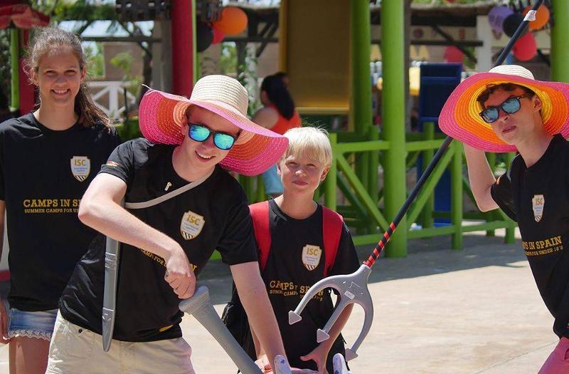 groupe de jeunes avec des accessoires comme des chapeaux roses et des épées en plastique lors d'une colo