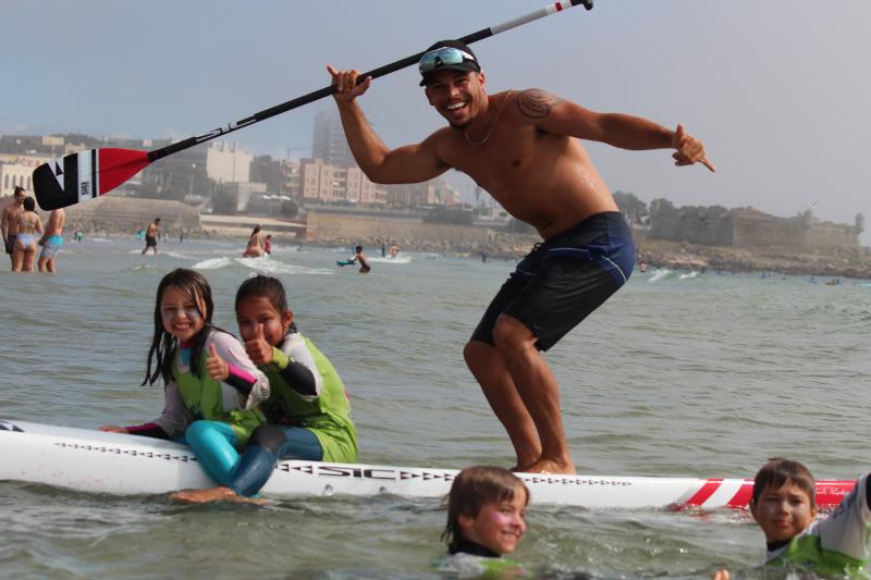 des enfants avec un moniteur sur une planche de paddle à la plage