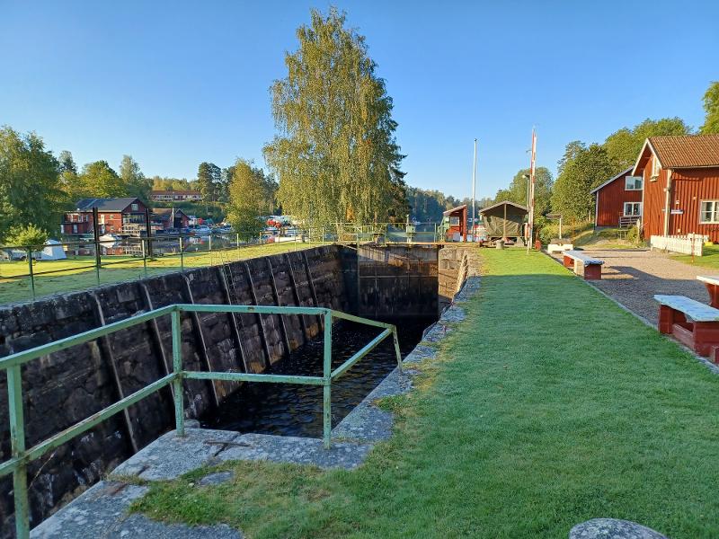 Vue sur le barrage du canal de la colo aventure en Suède, bandes d'herbe verte sur les côtés et le lieu du séjour entouré de nature en fond