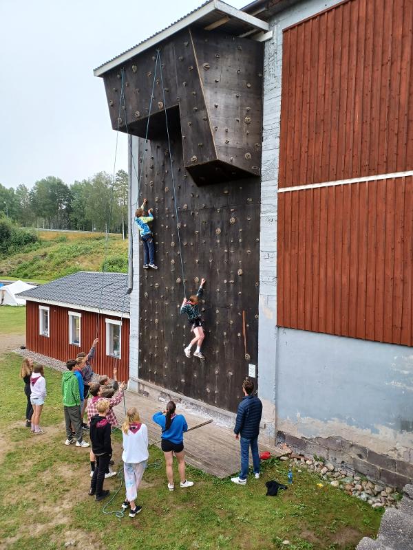 Groupe de jeunes vus de loin, près du mur d'escalade de la colo aventure en Suède, deux jeunes escaladent, les autres regardent