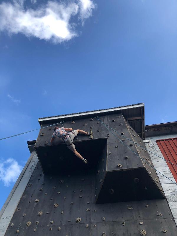 Jeune grimpant un passage surélevé du mur d'escalade de la colo aventure en Suède