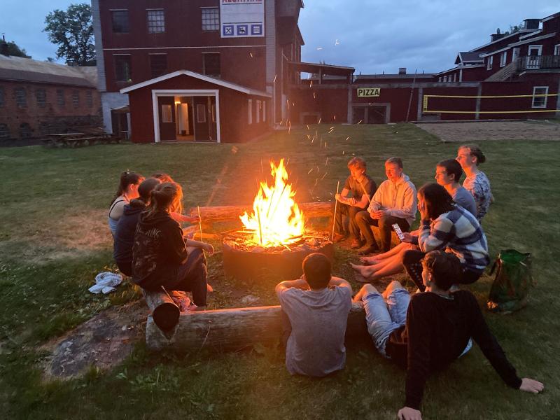 Jeunes réunis autour d'un feu de camp sur le lieu du séjour pendant la colo aventure en Suède