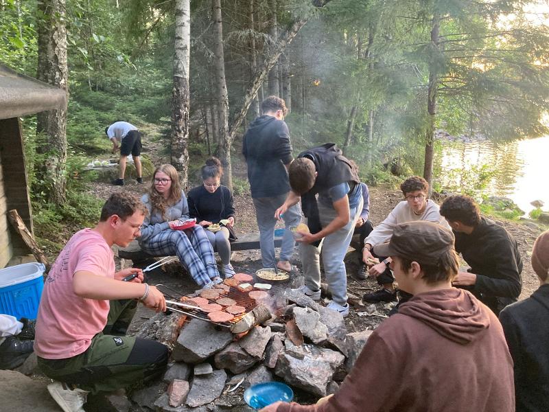 Préparation du repas sur feu de bois dans la forêt lors du camp itinérant en Suède