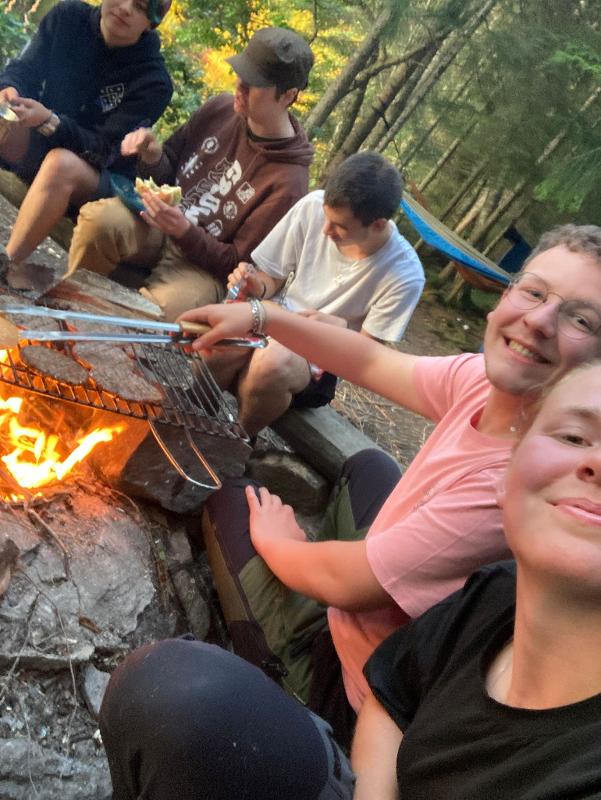 Selfie de jeunes préparant le repas sur feu de bois en forêt, pendant le camp itinérant en Suède