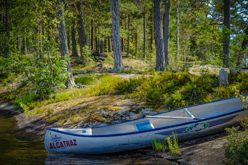Canoë posé sur la rive, avec la forêt verte en fond, pendant le camp itinérant en Suède