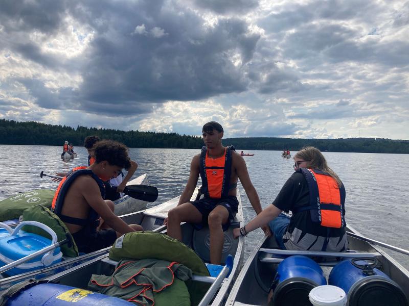 Jeunes en canoë sur l'eau sous un ciel nuageux lors du camp itinérant en Suède