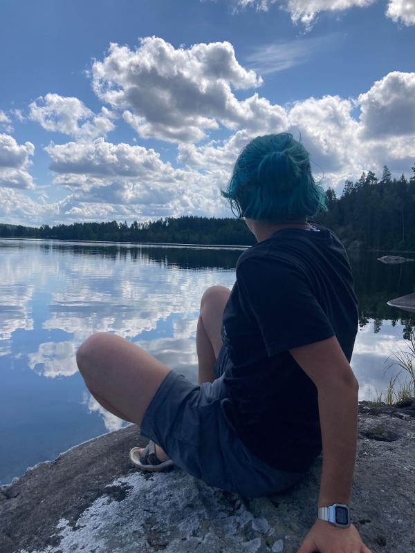 Jeune personne regardant vers l'eau et les reflets du ciel pendant le camp itinérant en Suède