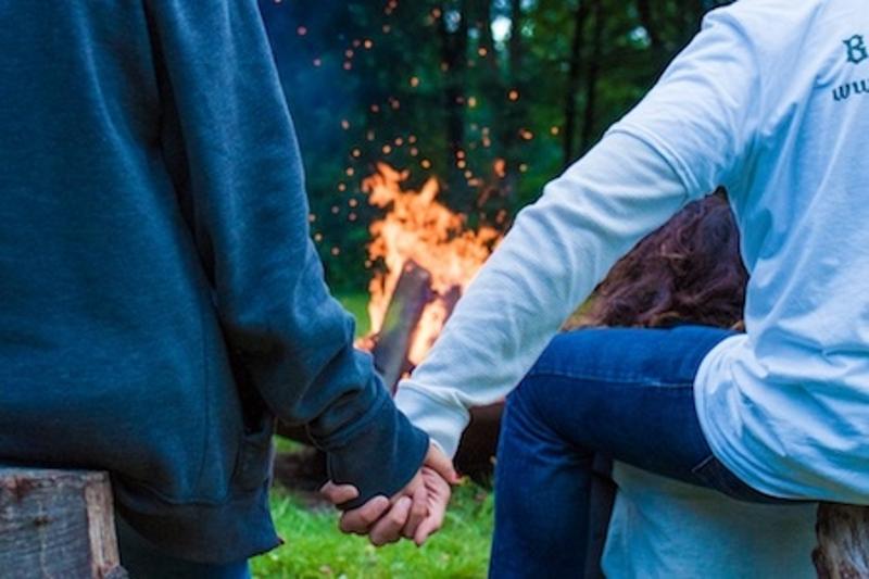 deux enfants se tiennent la main autour d'un feu de camp