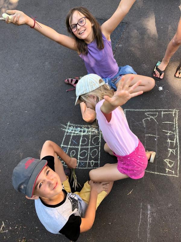 enfants qui jouent à ma marelle avec des craies au sol