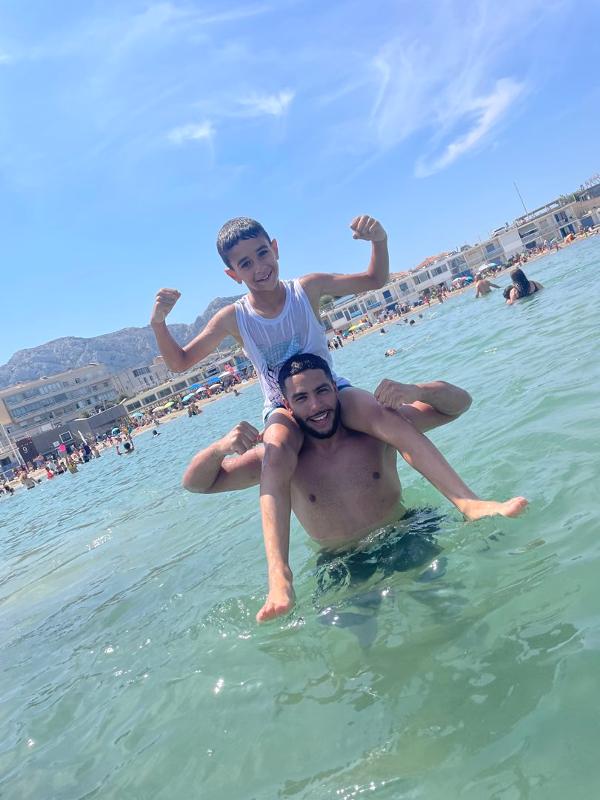 jeune garçon sur les épaules d'un animateur dans la mer en colo
