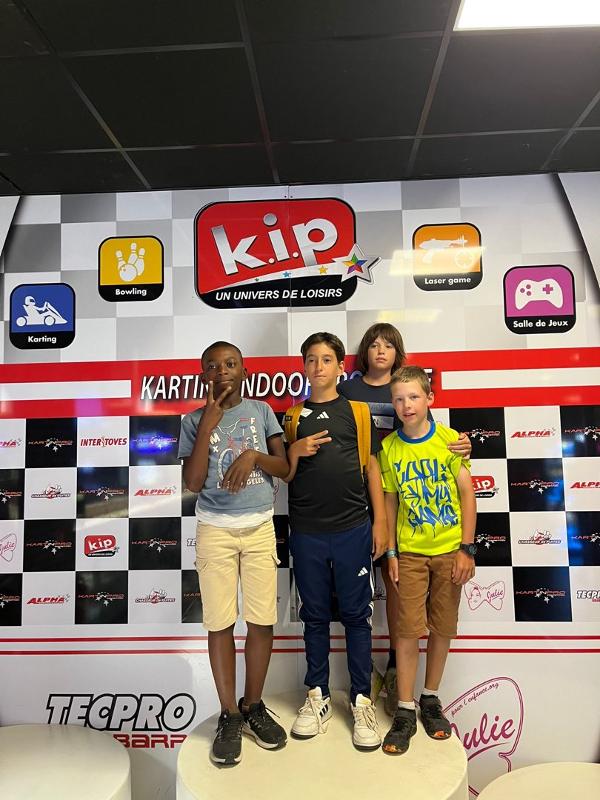 garçons qui posent pour la photo après avoir gagné la partie de karting en colo