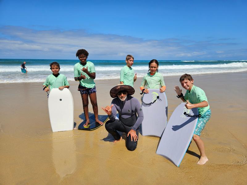 enfants avec des petites planches de surf avec le moniteur en colo