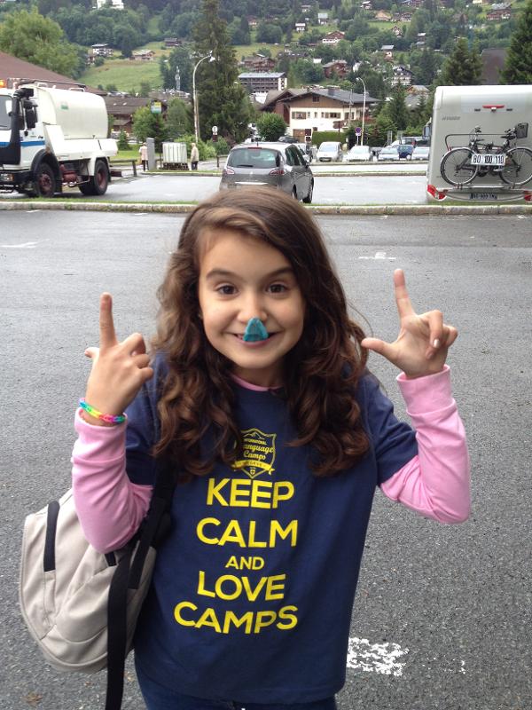 enfant qui pose avec un bonbon dans la bouche pour la photo en colo avec un t-shirt du camp