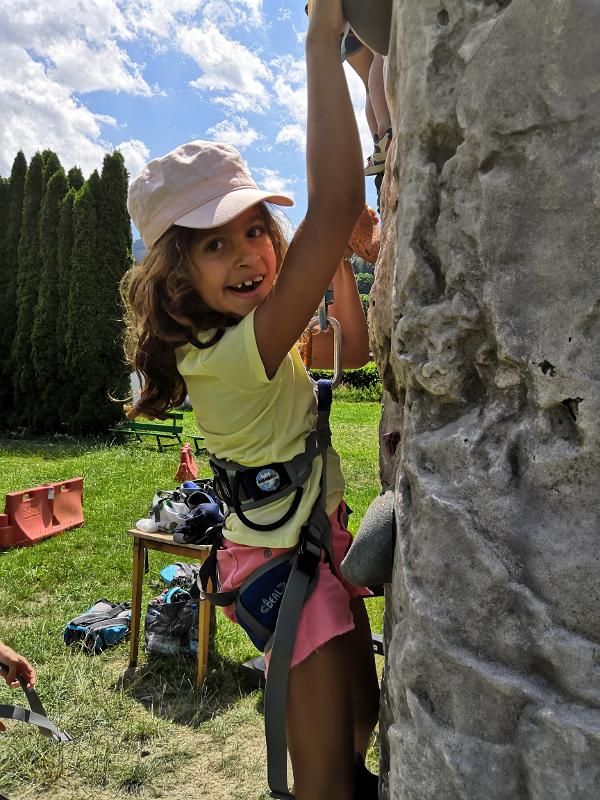 enfant qui fait de l'escalade sur un mur en plein air en toute sécurité lors de sa colo