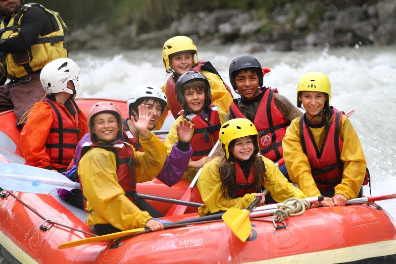 jeunes avec des ponchos et des casques qui font du rafting en colo
