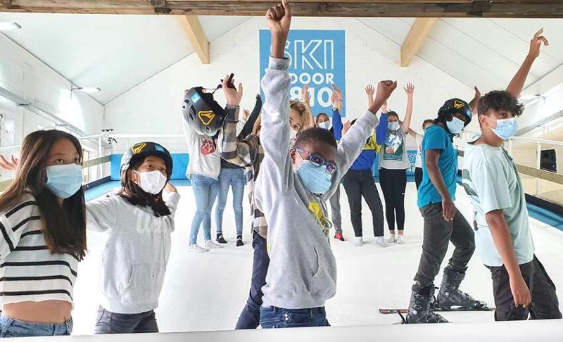 jeunes les bras levés lors d'une session de ski en intérieur en colonie ski