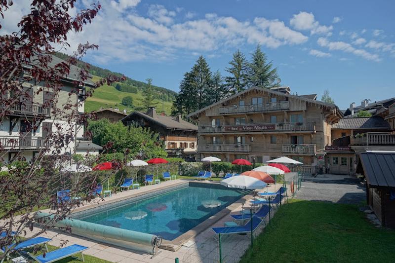 Hotel avec piscine avec des montagnes en fond lors des colos