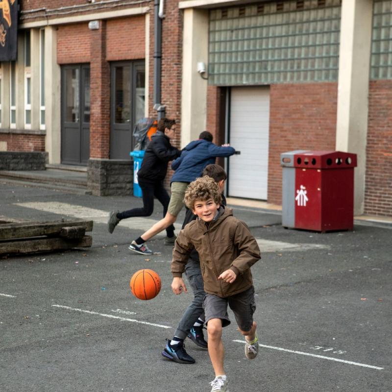 Un garçon avec un manteau qui court avec un ballon de basket