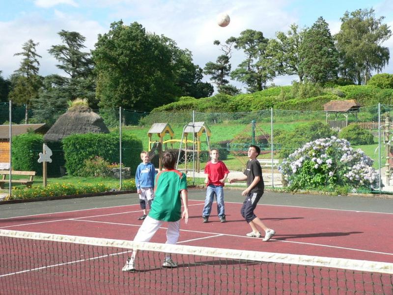 quatre jeunes en colos qui sont sur un court de tennis et qui s'amusent