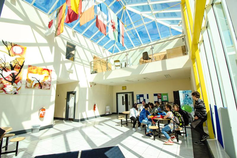 Des jeunes autour d'une table dans le hall d'accueil lumineux de leur séjour linguistique irlande