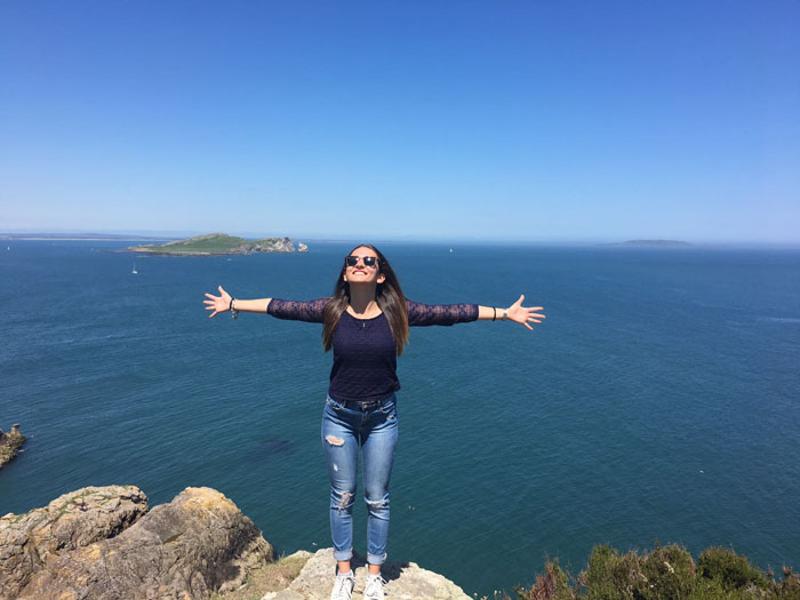 fille les bras écartés, visage vers le soleil au bord d'une falaise en séjour linguistique irlande