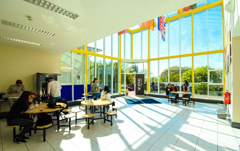 Hall de l'école de langue du séjour linguistique irlande avec des tables, des distributeurs partie avec murs totalement vitrés