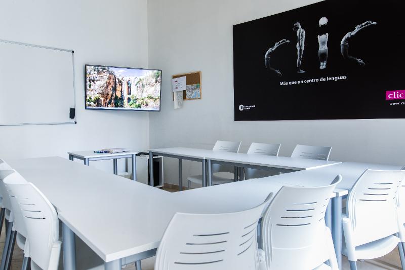 Salle de classe du séjour linguistique espagnol avec des tables, chaises, un tableau blanc et un écran 