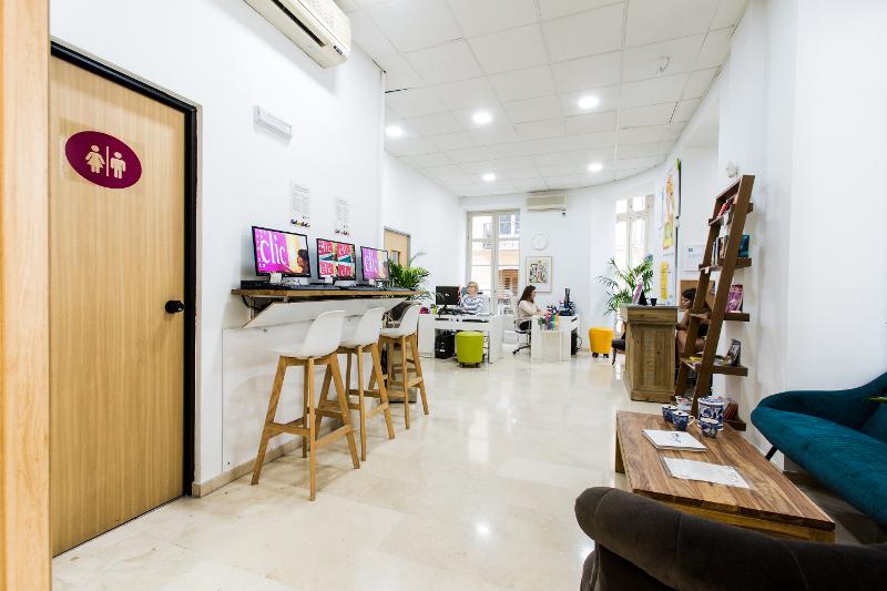 Espace commun de l'école du séjour linguistique espagnol avec un coin salon, des tables hautes avec des ordinateurs et des bureaux