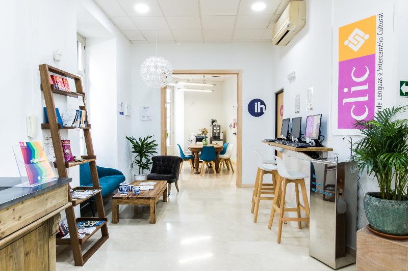Réception de l'école du séjour linguistique espagnol avec une fontaine à eau, un coin salon, des tables hautes avec des ordinateurs