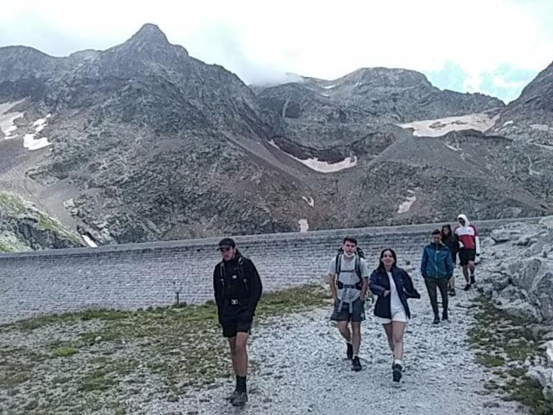 Jeunes qui font une randonnée sur un chemin avec la montagne en arrière-plan en colo montagne