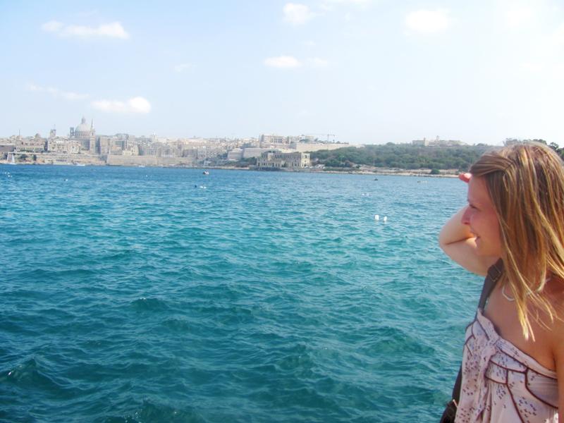 Fille du séjour linguistique malte regardant la mer au loin avec la ville en arrière plan 