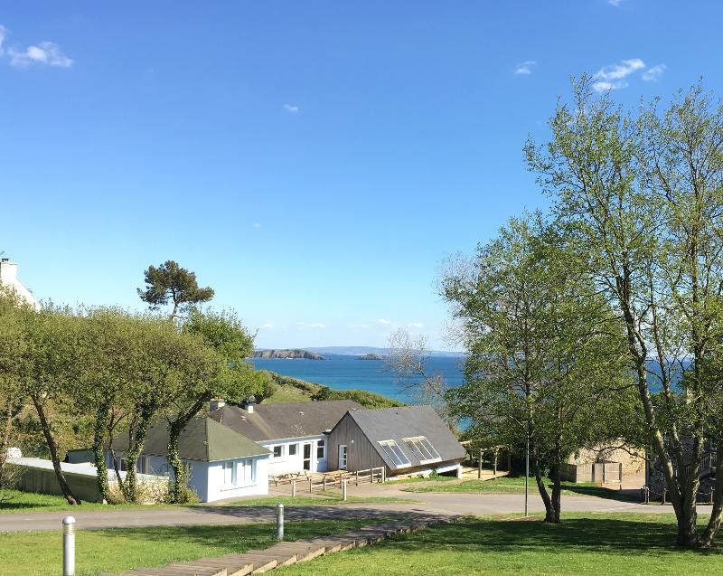 Vue sur des bâtiments avec les arbres autour et la mer au loin