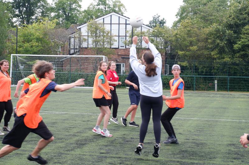 Jeunes avec des maillots de sport jouant à un jeu de ballon pendant leur séjour linguistique angleterre ado campus
