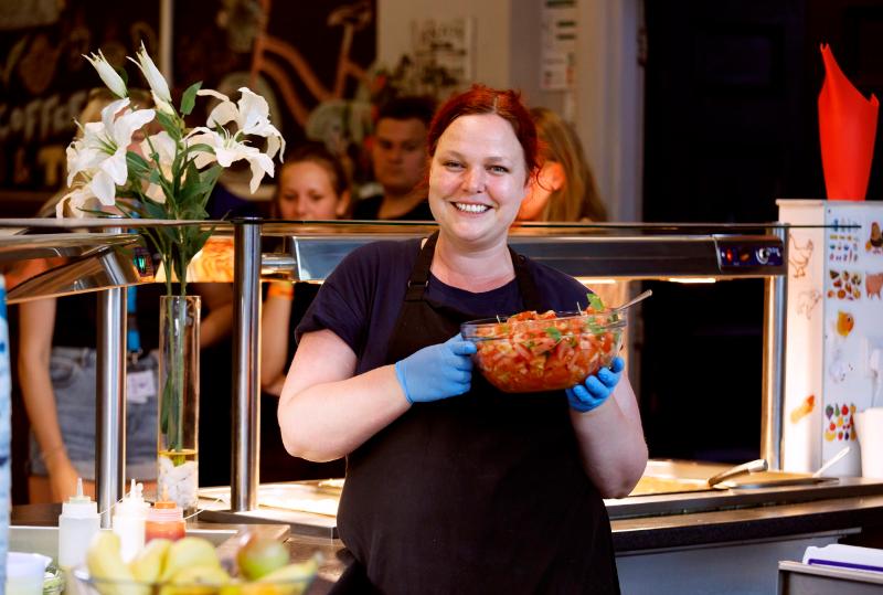 femme à la cantine avec un plat dans les mains en camp de vacances france