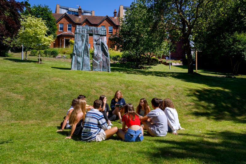 Groupe de jeunes d'un séjour linguistique Angleterre ado campus assis en cercle dans l'herbe