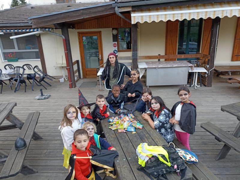enfants réunis à une table avec leur collecte de bonbons en colo halloween