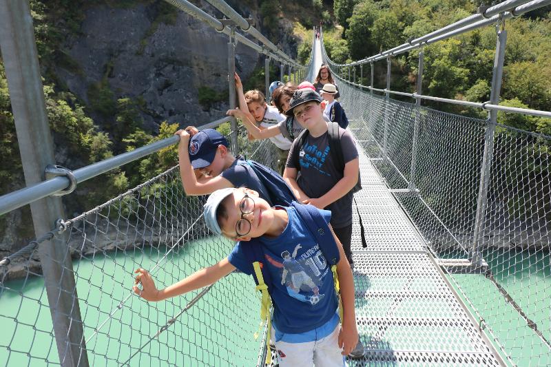  Groupe d’enfant à la file indienne sur un pont au dessus d’une eau turquoise 