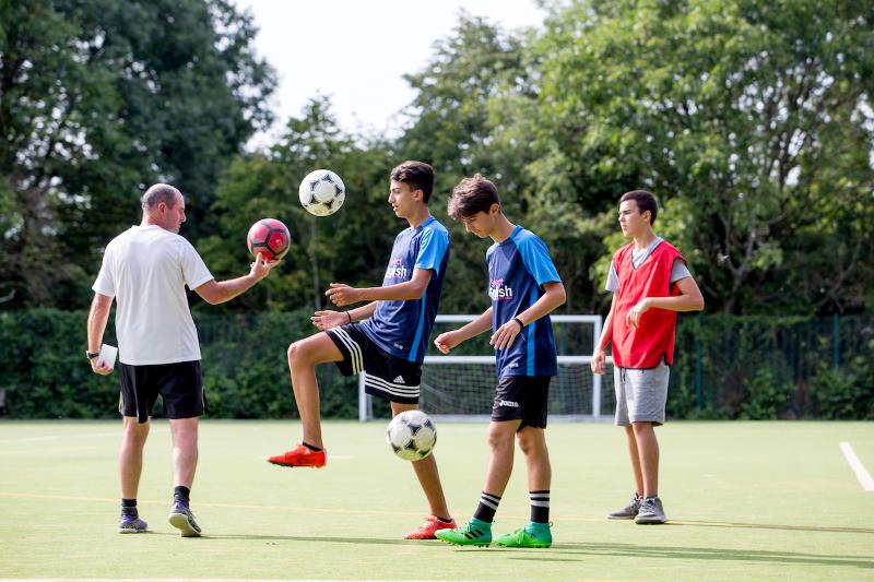 Des jeunes s'essayant au football avec un entraîneur pendant un séjour linguistique Angleterre et foot à Cambridge