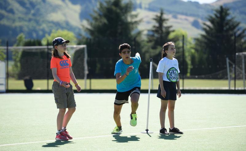 1 garçon qui court et 2 filles sur un terrain de sport pendant leur séjour linguistique écosse