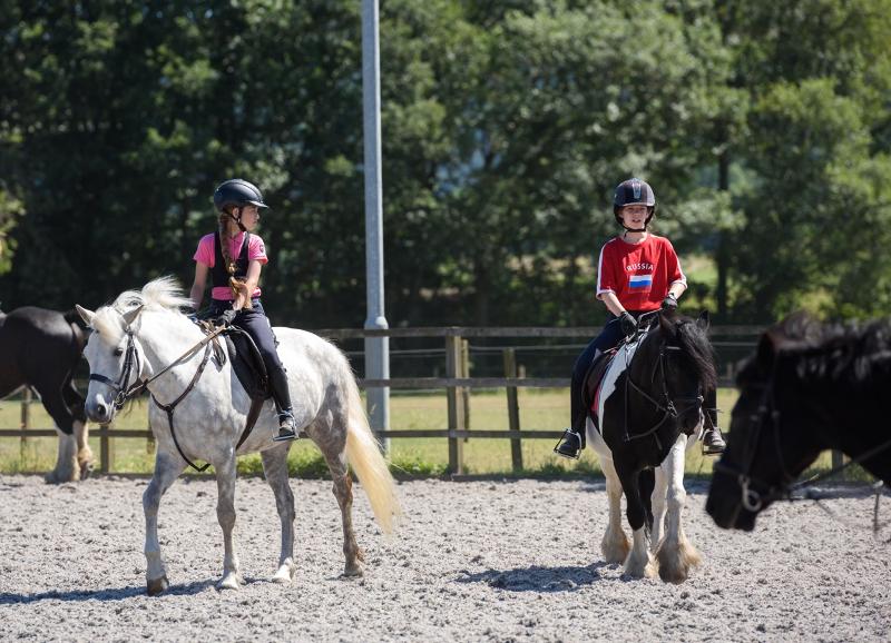 2 filles qui montent à cheval dans une carrière pendant leur séjour linguistique équitation Angleterre